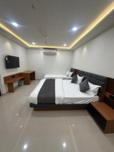 a bedroom with a large bed and a television at Hotel Peacock Anand in Anand