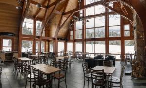 a restaurant with tables and chairs in a room with large windows at Gîte du Mont-Albert - Sepaq in La Martre