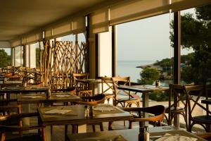 a restaurant with tables and chairs and a view of the ocean at Sandos El Greco - Adults Only in Portinatx