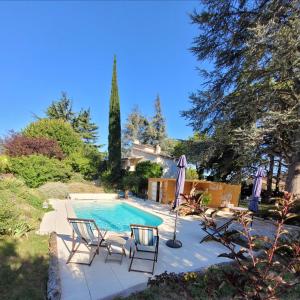 a swimming pool with two chairs and an umbrella at chambres d'hôtes BARTAV aile in Espeluche