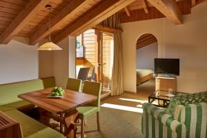 a living room with a wooden table and green chairs at Hostellerie am Schwarzsee in Bad-Schwarzsee