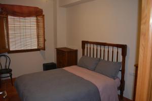 a bedroom with a bed with blue pillows and a window at Casa Paola in Buñol