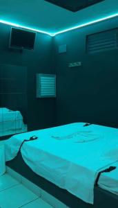 a bed in a room with a blue light at Classik Prime Motel in Araçatuba