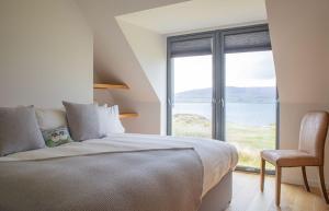 a bedroom with a bed and a chair and a large window at Cnoc Na Lobhta in Husabost