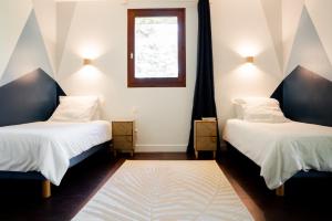two beds in a room with a window and a rug at Gîte Le Cot en Vallée d'Ossau in Sainte-Colome