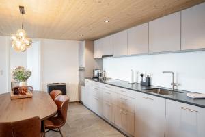 a kitchen with white cabinets and a wooden ceiling at Casa Lago in Tüscherz-Alfermée