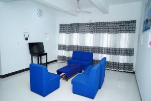 a living room with blue chairs and a tv at Elite moon hotel in Kallady