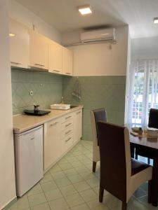 a kitchen with white cabinets and a table with chairs at Apartmani Milojić in Soko Banja