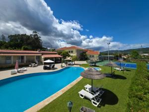 a swimming pool with chairs and umbrellas at Quinta Dom José Turismo Rural in Braga