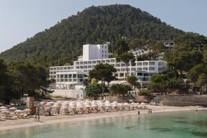 a building on a beach with chairs and umbrellas at Sandos El Greco - Adults Only in Portinatx
