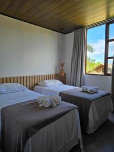 two beds in a room with a window at Portal do Kite in Barra Grande