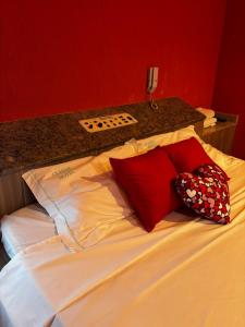 a bed with red and white pillows on it at Classik Prime Motel in Araçatuba +6 photos