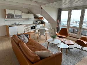 a living room with a couch and tables and a kitchen at Panoramaudsigt og swimmingpool midt i Ebeltoft in Ebeltoft