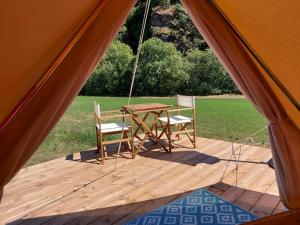 a tent with a table and chairs on a porch at Glamping Luz Olive in Combret