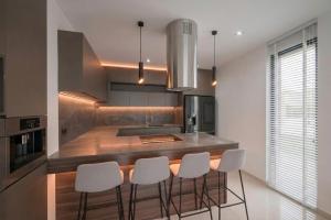 a kitchen with a island with white bar chairs at Villa JAM in Kaštela