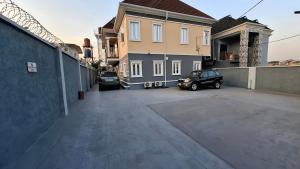 a parking lot with two cars parked in front of a house at Cherished Homes in Ikeja