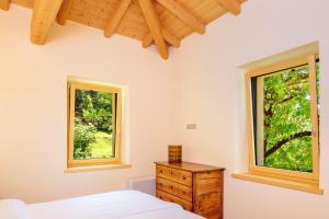 a bedroom with two windows and a bed and a wooden dresser at Chalet Ca' la Fratela in Malcesine