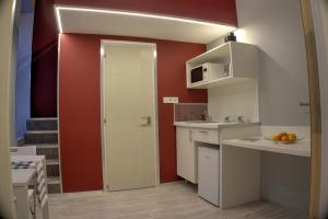 ブダペストにあるHILD-1 Apartmentsの白いキャビネットと赤い壁のキッチン