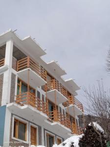 a white building with wooden balconies in the snow at Nimat Nivas By Fuwa Homestay in Vashisht