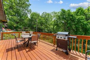 a wooden deck with a grill and a table with chairs at Whispering Bass Lodge 3BDR in Kimberling City