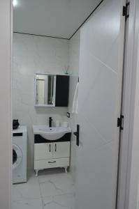 a white bathroom with a sink and a mirror at PushkinApart in Batumi +11 photos