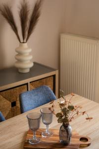 a wooden table with two glasses and a vase with flowers at Ithaki Apartments in Paramythia