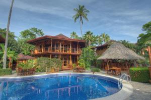 a resort with a swimming pool in front of a building at Tambor Tropical Beach Resort- Adults Only in Tambor