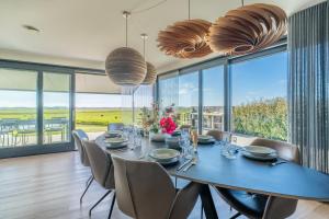 a dining room with a table and chairs and large windows at Natuurvilla 16 Weegeswaal in De Waal
