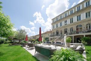 a courtyard with chairs and umbrellas in front of a building at Pavillon des Millésimes in Lussac