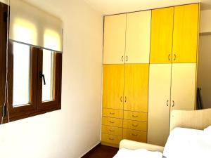 a bedroom with yellow and white cabinets and a window at Sergio's homes in Mélanes