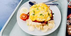 a white plate of food with an egg and potatoes at Hana hostel in Labuan Bajo