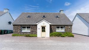 a brick house with a white door and a roof at Perewinkle Cottage - Portmagee in Lateeve