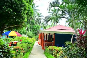 a small house with a rainbow umbrella next to a garden at SUN SHINE RESORT in Neil Island