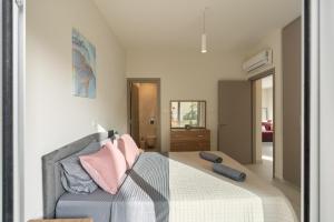 a bedroom with a bed with pink pillows on it at The Icon 001 - Superior 2BR Apartment with Pool & Gym, Mythical Seas - Protaras in Paralimni +44 photos