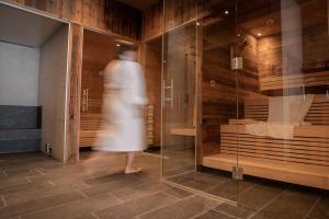 a woman in a white dress walking past a glass room at Palazi Apartments & Spa - Bike, Ski & Wellness in Nauders in Nauders +73 photos