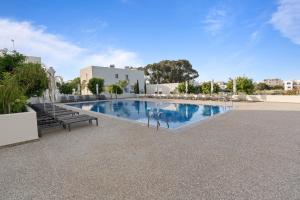a large swimming pool with two benches next to a building at The Icon 001 - Superior 2BR Apartment with Pool & Gym, Mythical Seas - Protaras in Paralimni