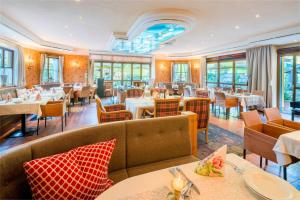a restaurant with tables and chairs and windows at Hotel Vitaler Landauerhof in Schladming