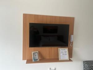 a flat screen tv in a wooden box on a wall at Casa da Dinda102 in Rio das Ostras