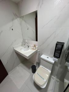a white bathroom with a toilet and a sink at Casa da Dinda102 in Rio das Ostras +6 photos