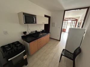 a kitchen with a stove and a sink and a refrigerator at Casa da Dinda102 in Rio das Ostras