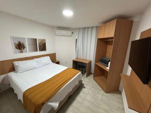 a hotel room with a bed and a flat screen tv at Casa da Dinda102 in Rio das Ostras