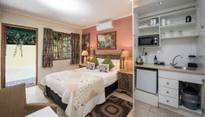 a bedroom with a bed and a kitchen with a sink at Algoa Guest House Summerstrand in Port Elizabeth