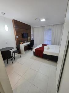 a bedroom with a bed and a desk and a table at Flat perto da Esplanada | SHN in Brasília