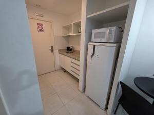 a small kitchen with a microwave on top of a refrigerator at Flat perto da Esplanada | SHN in Brasília