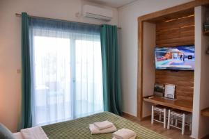 a bedroom with a bed and a tv and a window at Soultana’s house in Mourteri