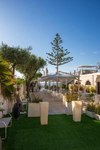 a patio with white chairs and trees and grass at Sunset Beach Club Tropea in Tropea