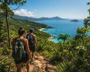 two people walking on a trail overlooking the ocean at Bouganvile Hostel Ilha Grande in Abraão