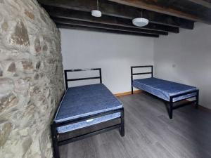 two beds in a room with a stone wall at Cwm Clyd - Carthouse in Rhayader