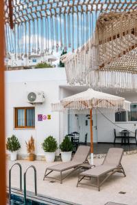 a patio with two chairs and an umbrella next to a pool at Vila Finnley in Ksamil