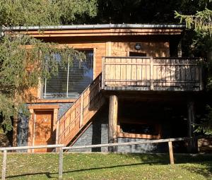 a house with a deck with a dog under it at Entre les Arbres in Saint-Jean-d'Aulps